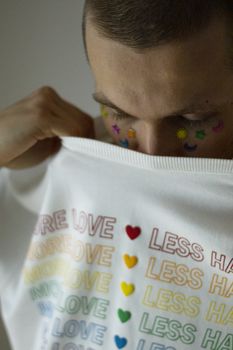 Close-up of a person holding a rainbow Love shirt, embracing identity.