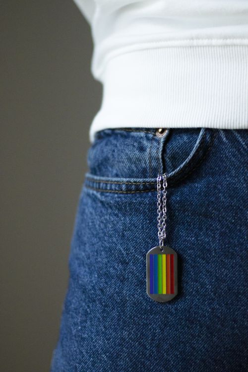 Free A vibrant rainbow pendant hanging on denim jeans. Symbol of LGBTQ pride. Stock Photo