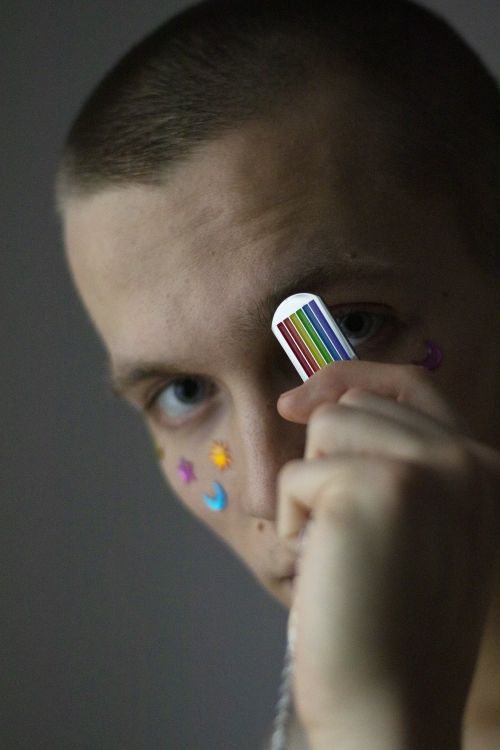 Free Young man with vibrant body art and rainbow stickers in artistic indoor portrait. Stock Photo