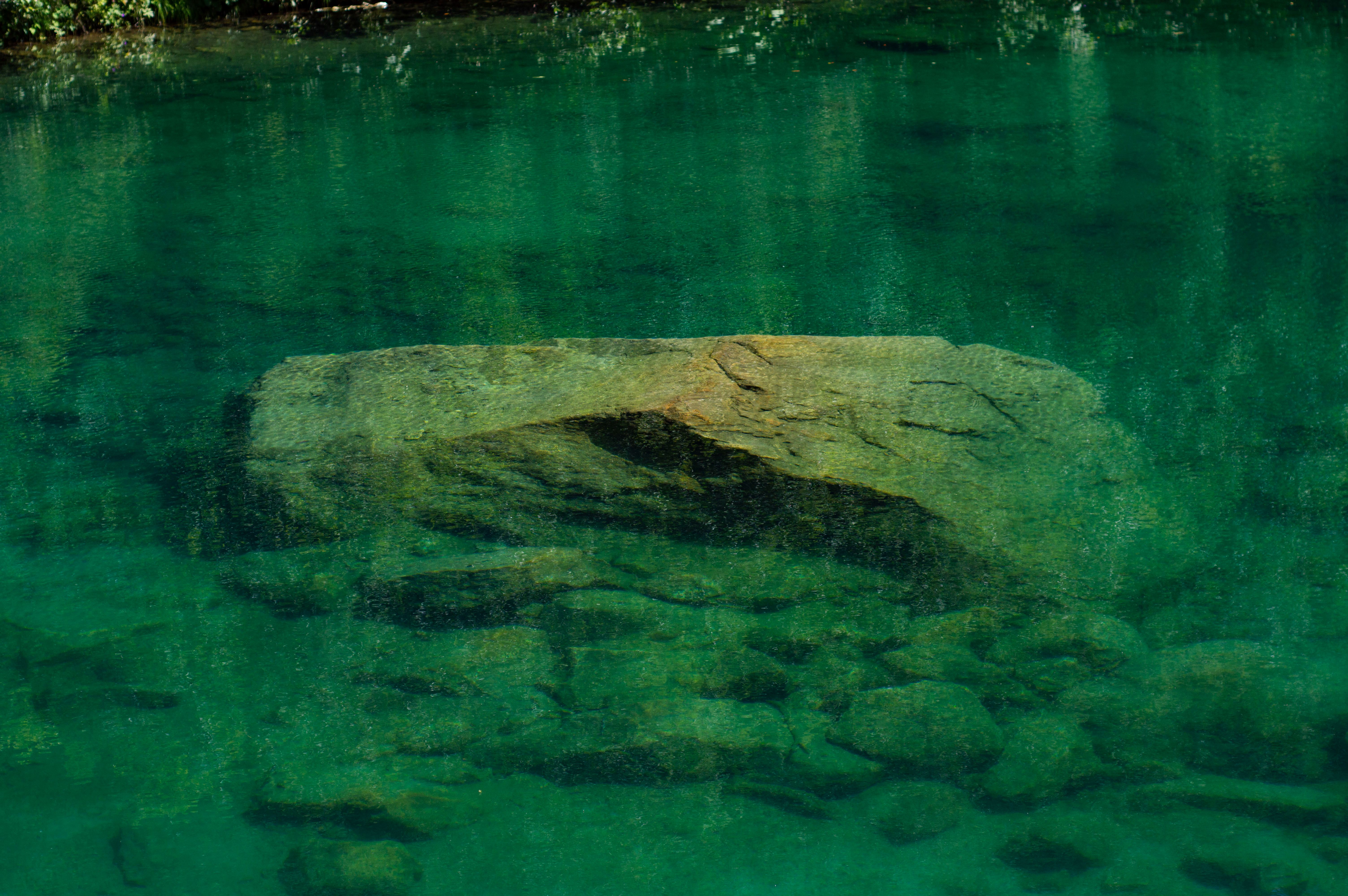 Serene and tranquil view of submerged rocks in crystal clear lake waters, reflecting natural beauty.