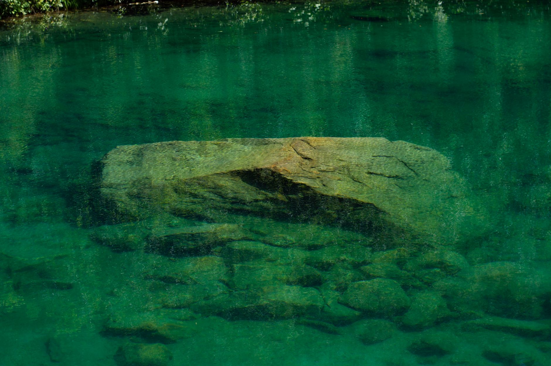Serene and tranquil view of submerged rocks in crystal clear lake waters, reflecting natural beauty.