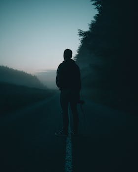 Silhouette of a person standing on a foggy road in Wicklow, Ireland during twilight.
