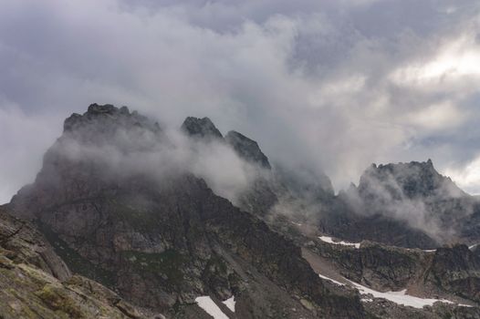 Foggy mountain peaks partially obscured by mist, creating a dramatic and moody atmosphere.