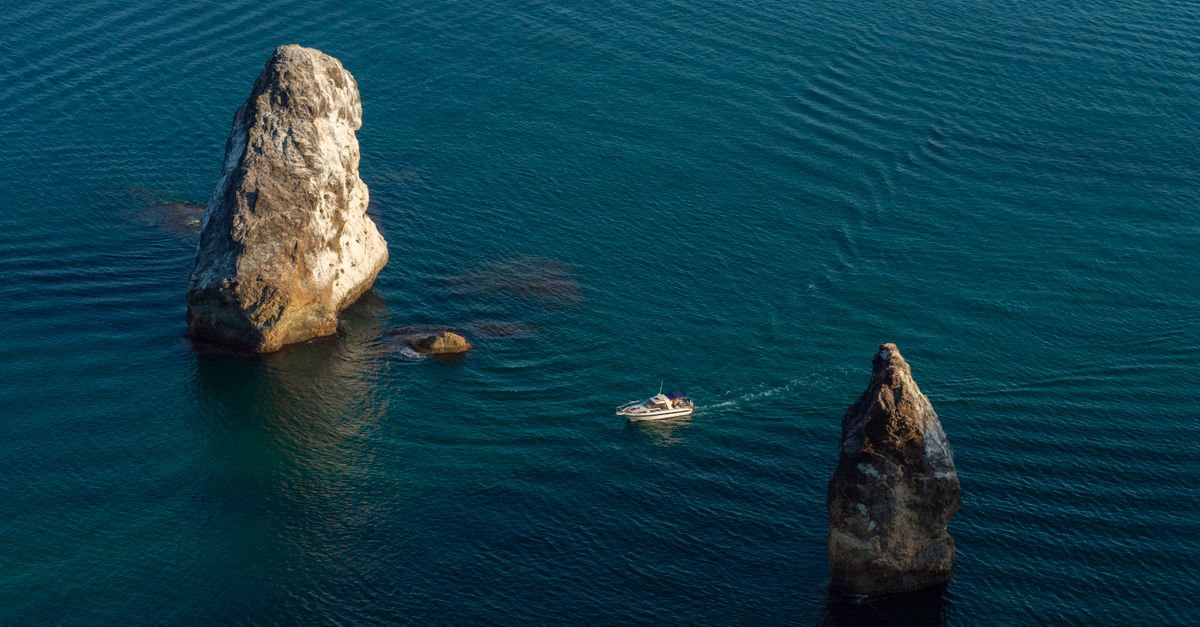 Ship Sailing Between Two Rock Formations in a Sea · Free Stock Photo