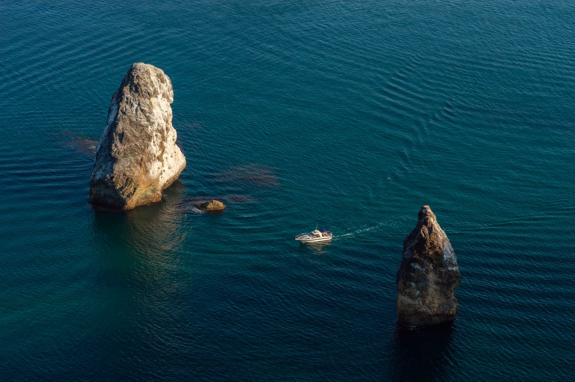 Ship Sailing Between Two Rock Formations in a Sea · Free Stock Photo