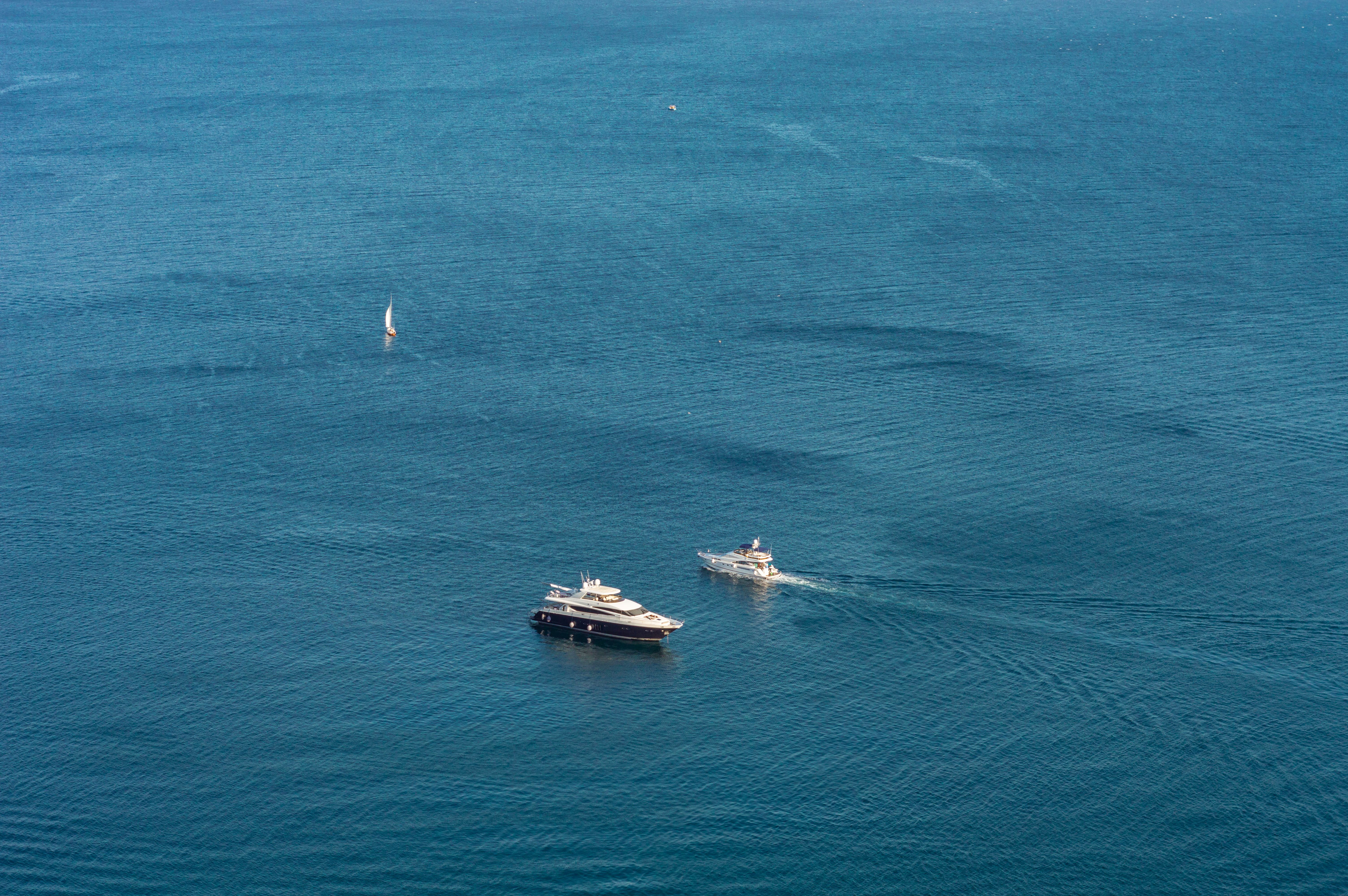 A panoramic view of a luxury yacht anchored near a coastline with a classic luxury train visible in the distance.