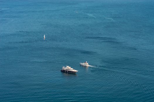A stunning aerial view of yachts and a sailboat navigating the expansive blue sea, showcasing nautical adventure.