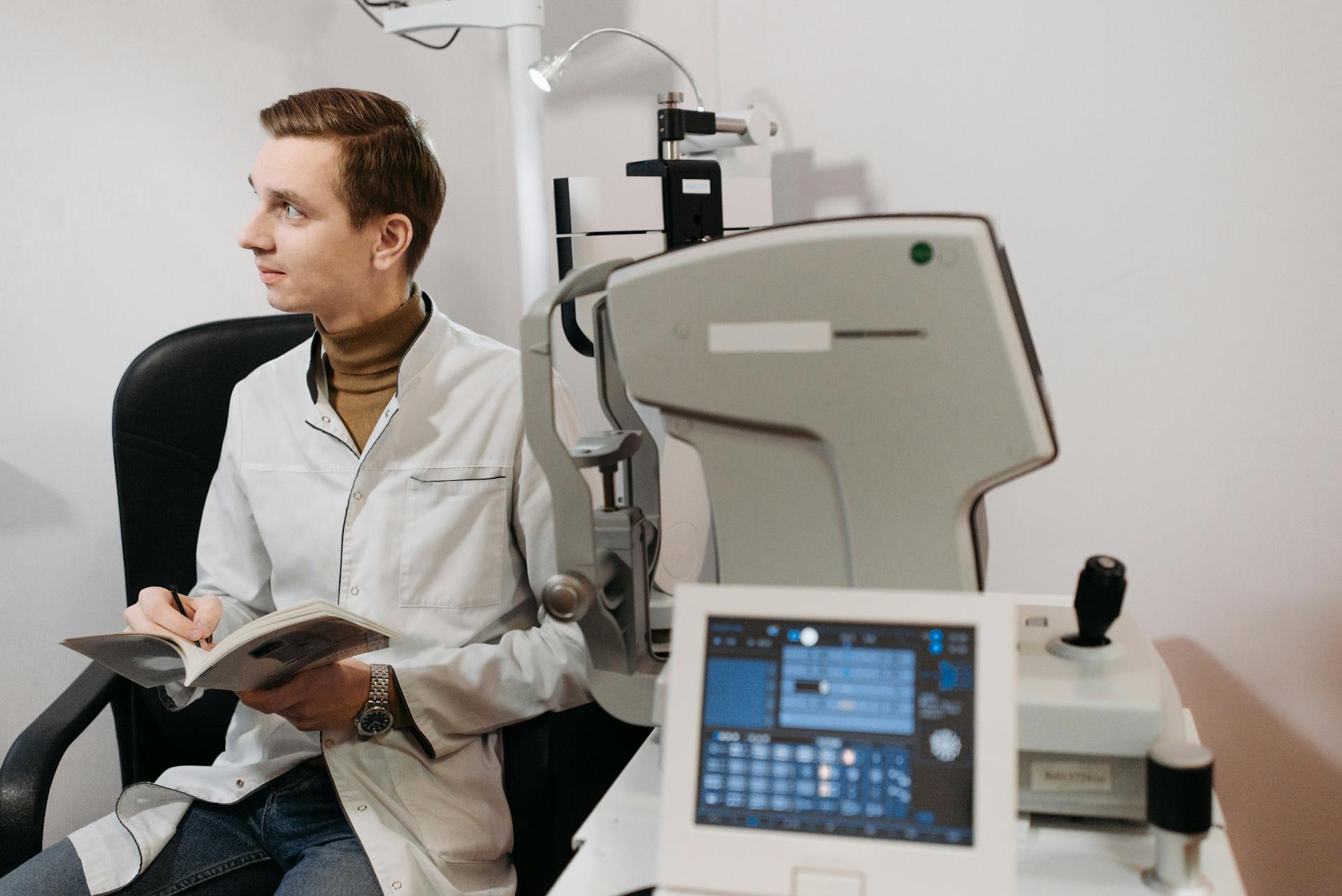 A medical professional reading in an office with advanced diagnostic equipment.