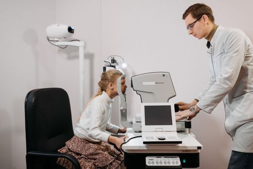 Free A young girl receives an eye exam from an optician in a clinical setting, focused on vision health. Stock Photo