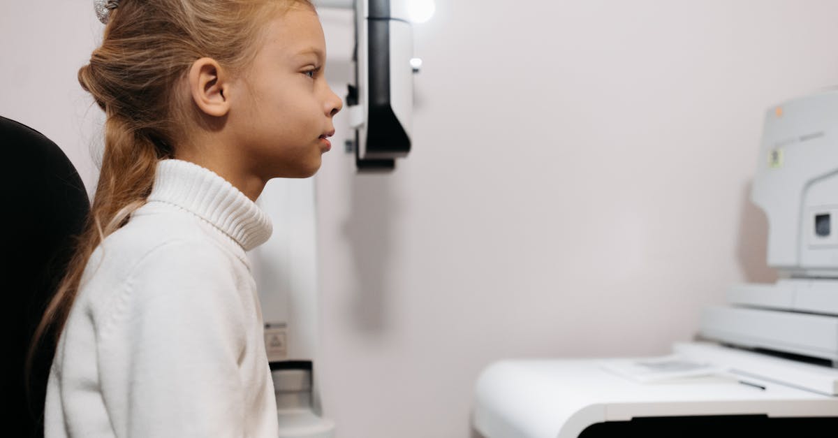 A young girl sits attentively during an eye examination with modern medical equipment.