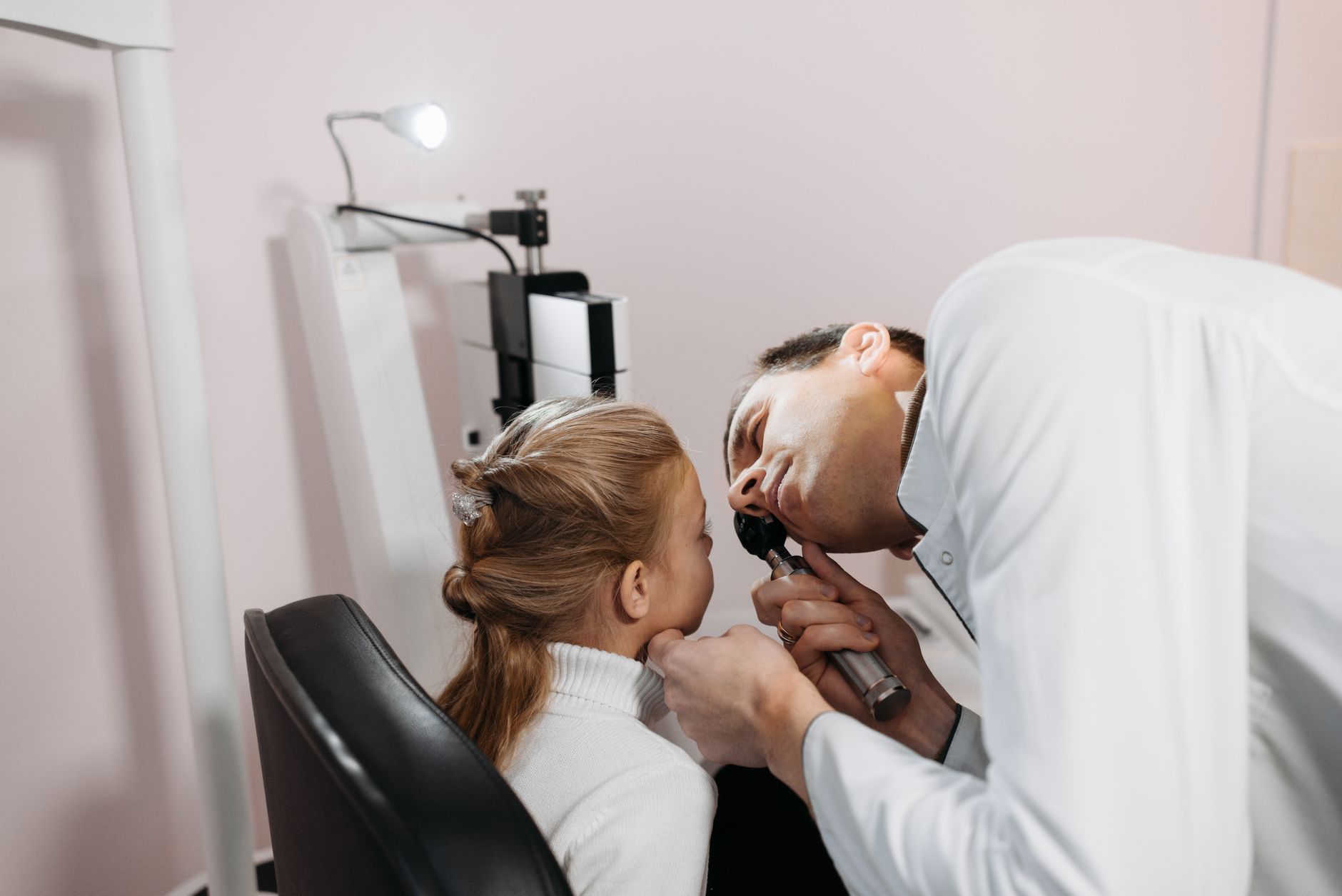 A doctor examines a young girl's ear during a medical appointment in a clinic.