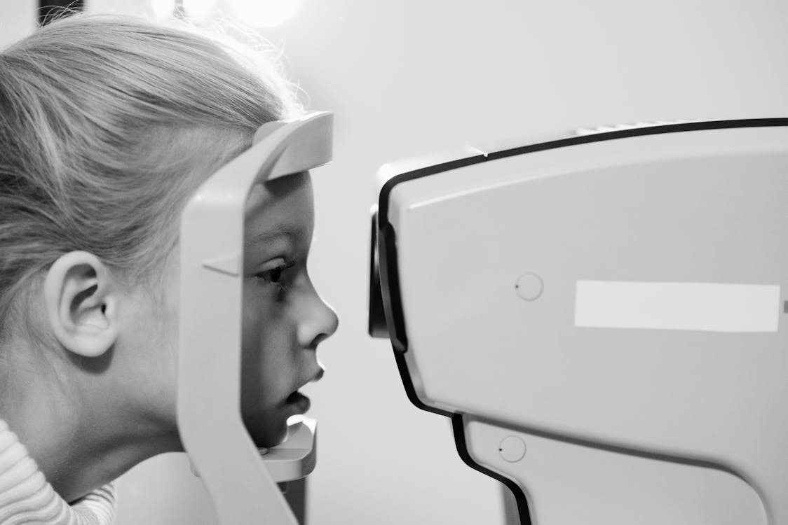 Free A Girl Resting Chin on an Eye Testing Equipment Stock Photo