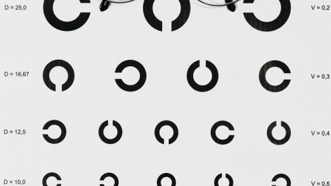 Close-up of an eye examination chart with eyeglasses on top, highlighting vision testing.