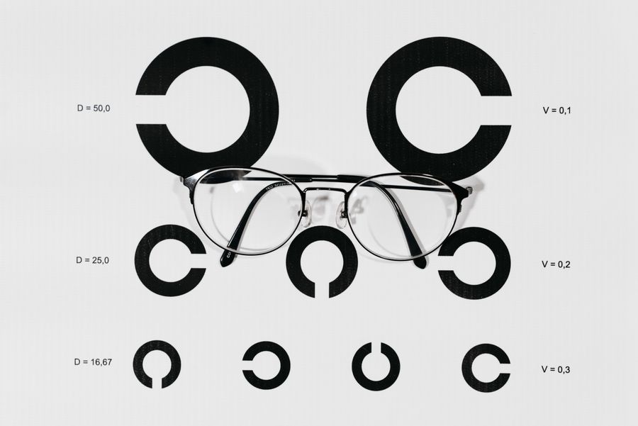 Eyeglasses resting on a Snellen vision chart — representing clinical eye health research