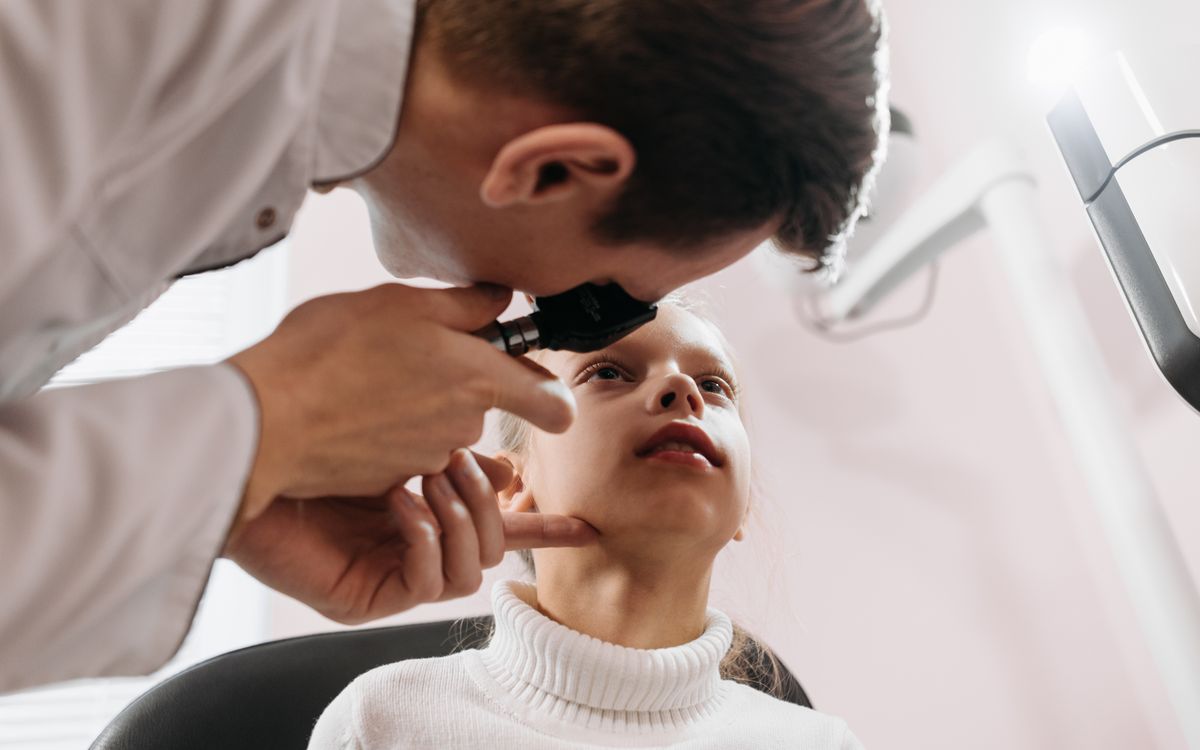 Doctor performs an eye examination on a young girl in a clinic setting, showcasing pediatric healthcare.