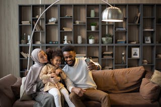 Delighted multiethnic family taking selfie sitting on couch