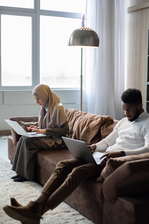 Uomo E Donna Seduta Sul Divano Utilizzando Macbook