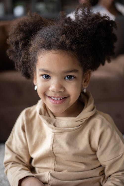 Adorable happy African American little girl in casual wear with earrings looking at camera
