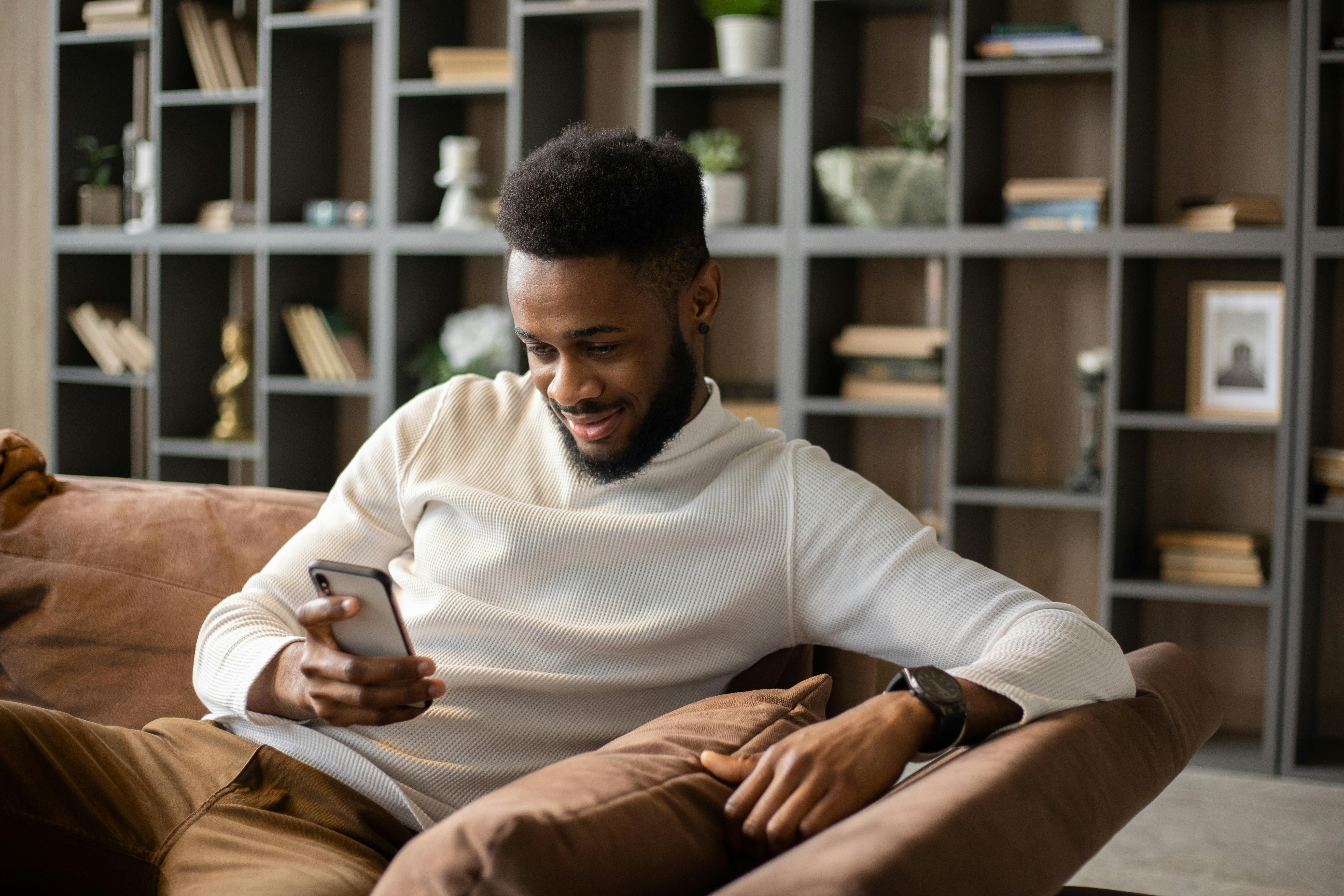 smiling young black man having video call at home