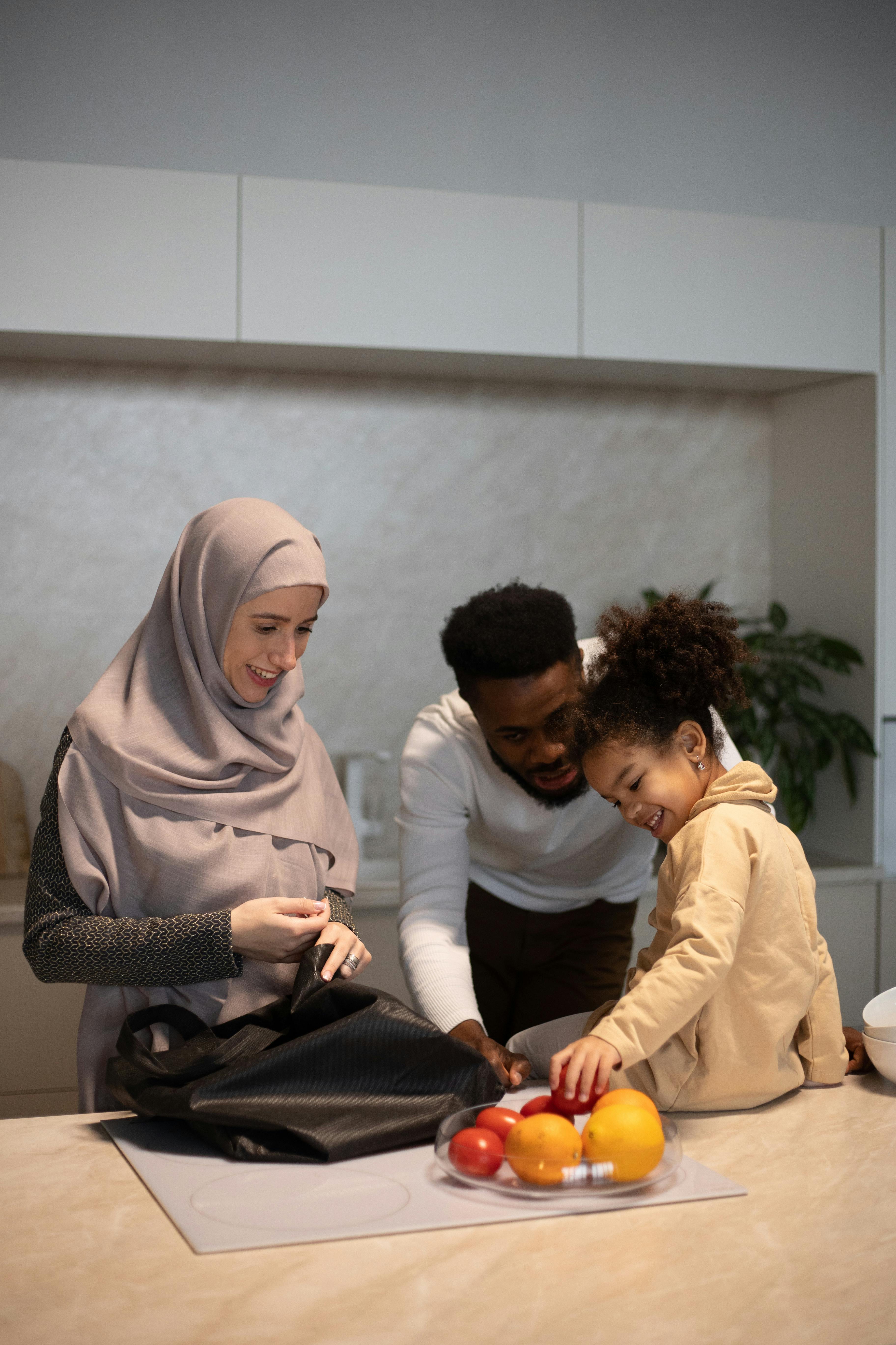 positive multiethnic family near table with fruits in kitchen