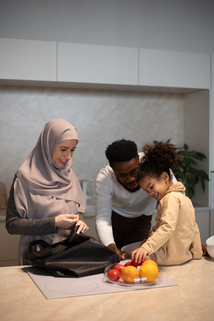 Positive Multiethnic Family Near Table With Fruits In Kitchen