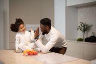 Black father with daughter near table with fruits in kitchen