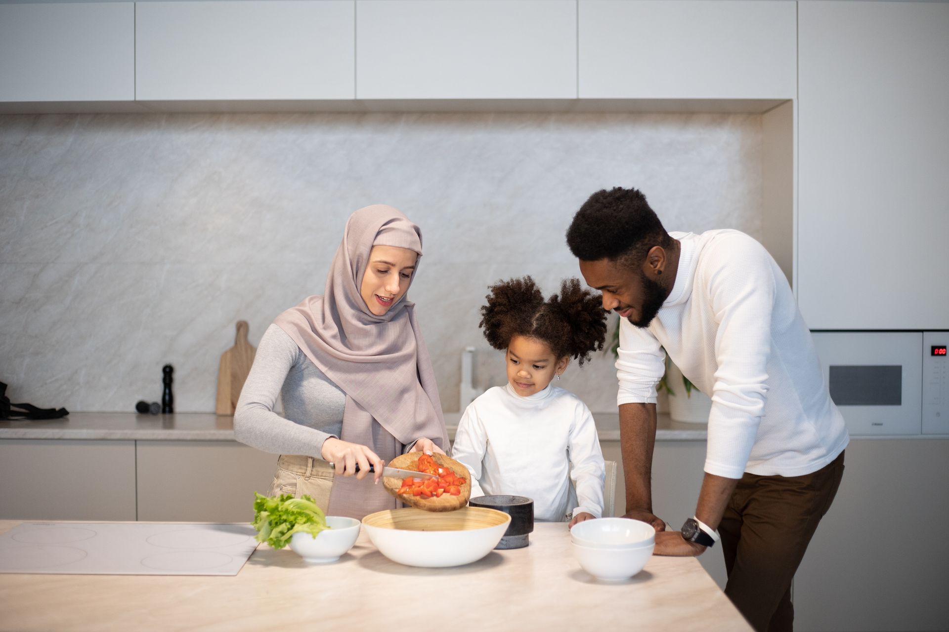 Delighted young diverse family standing near table in kitchen at home while cooking together at home