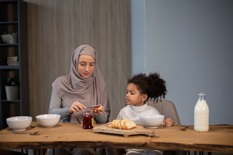 Diverse Mother And Daughter At Table Having Breakfast