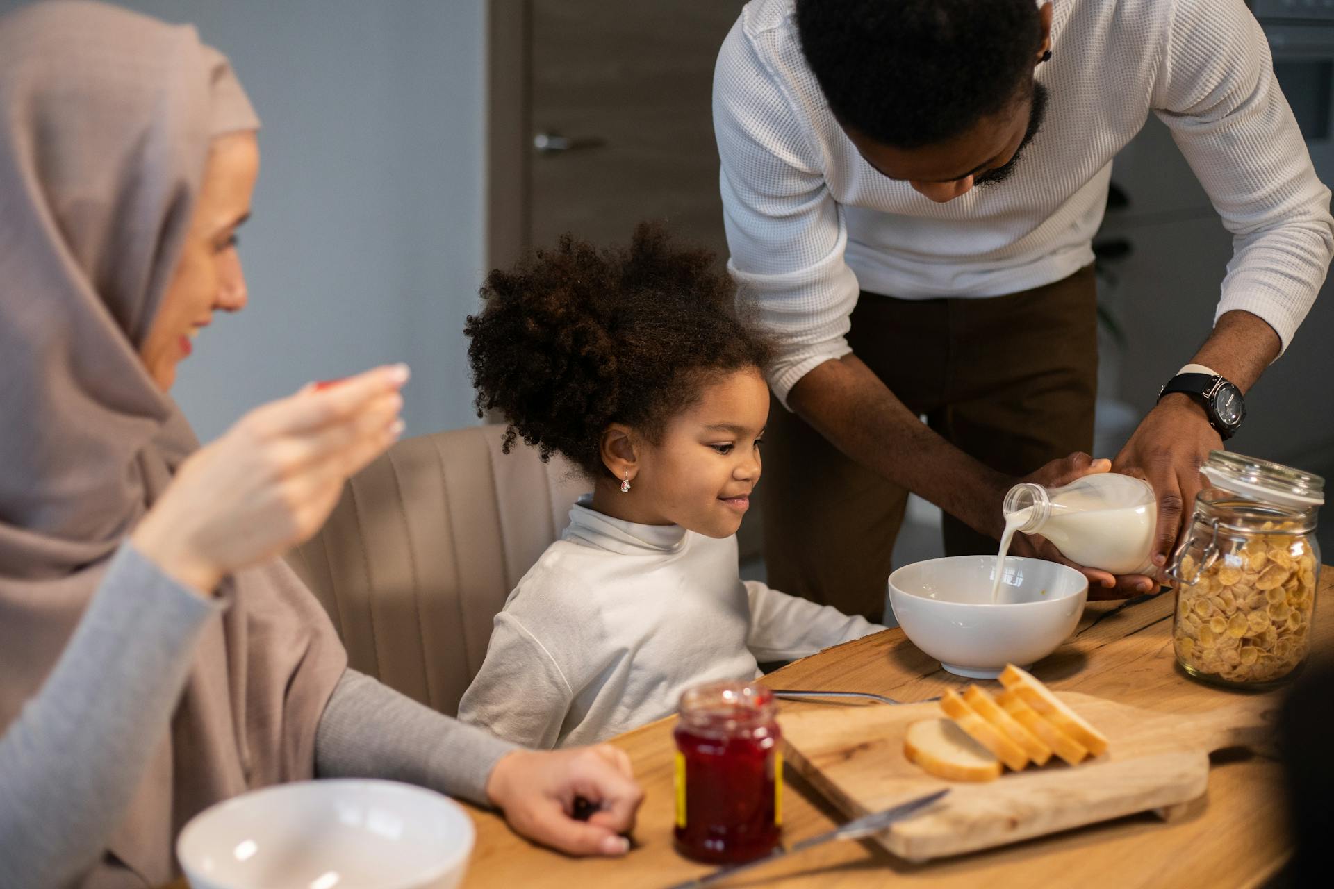 Cheerful diverse family having breakfast with milk and cereals