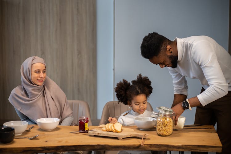 Glad Family Having Breakfast At Table