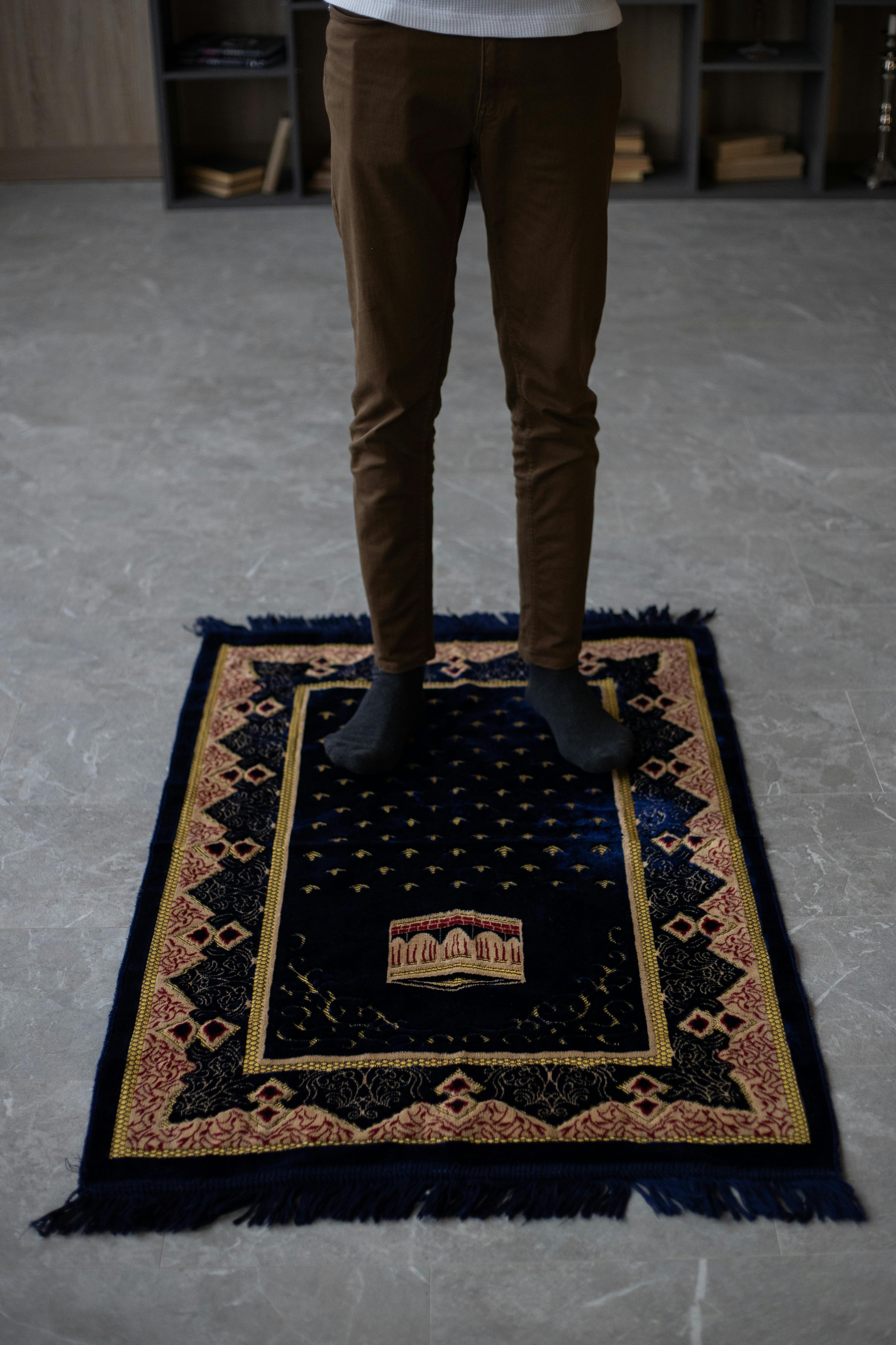 crop man standing on mat before praying at home