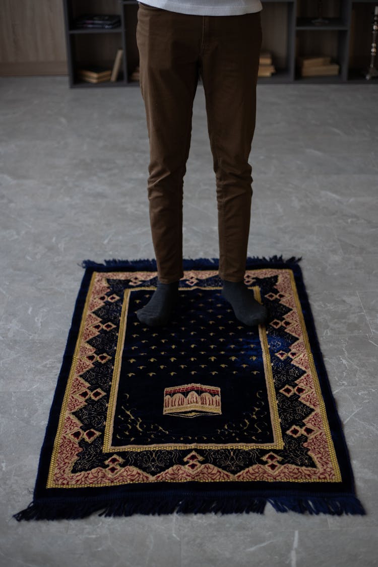 Crop Man Standing On Mat Before Praying At Home