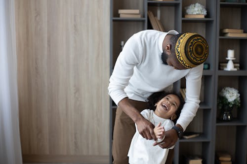 Cheerful black father having fun with cute daughter