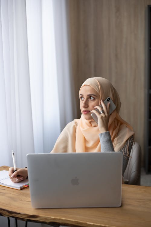 женщина в бежевом хиджабе на серебряном Macbook