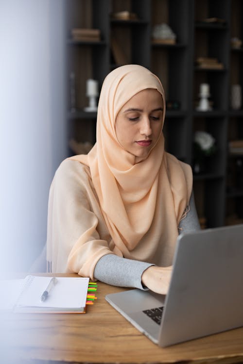 Serious Muslim businesswoman browsing contemporary netbook at home
