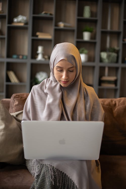 Macbook을 사용하는 갈색 Hijab의 여자