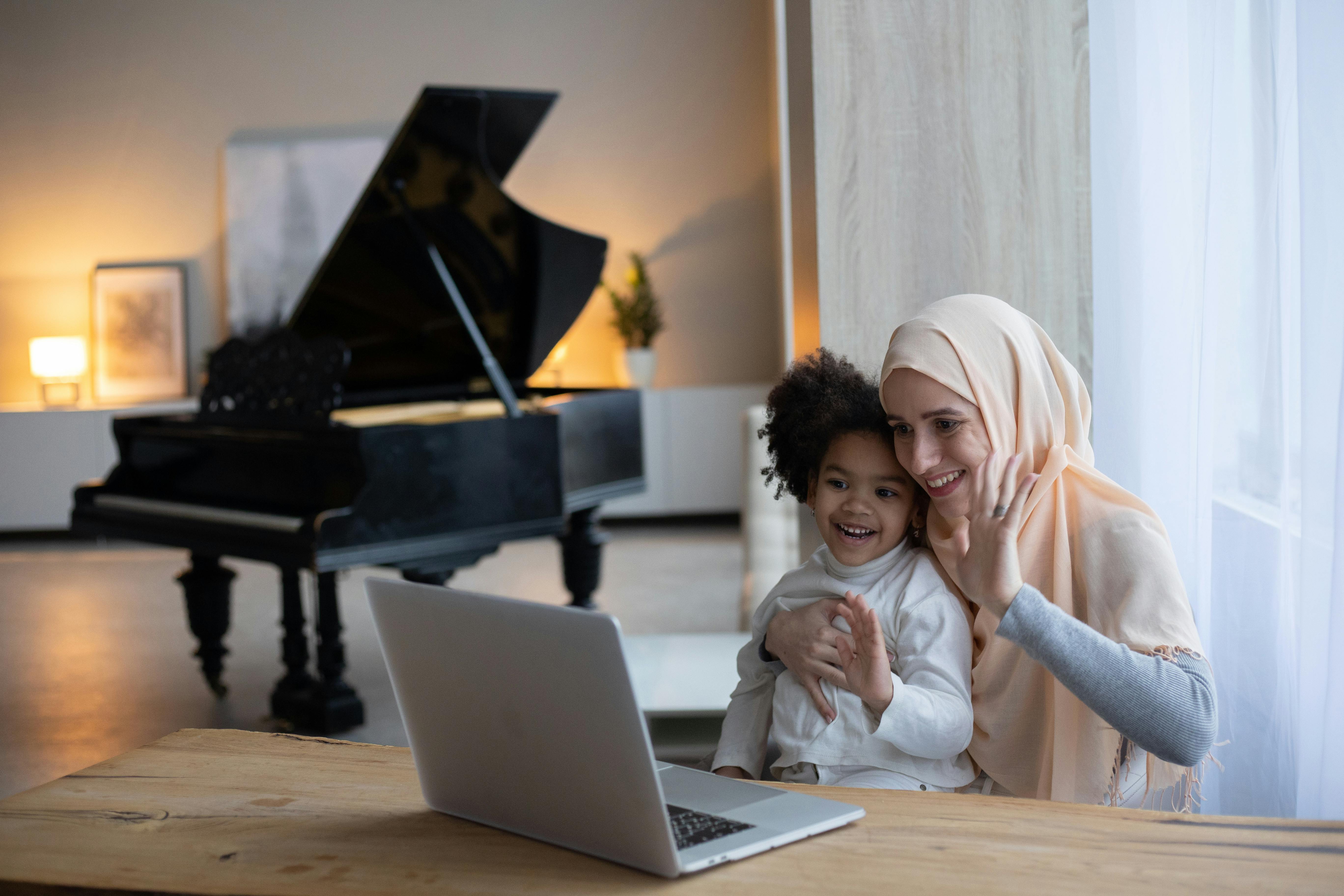 positive muslim mother and black girl having video call on laptop