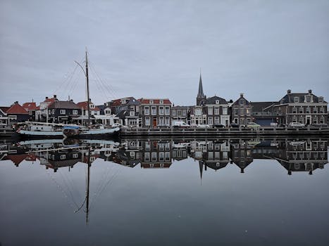 Charming waterfront view with boats and houses perfectly mirrored on a calm lake in a picturesque town.