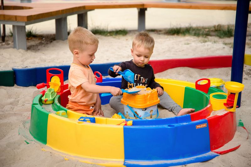 Two young children playing in a colourful sandpit