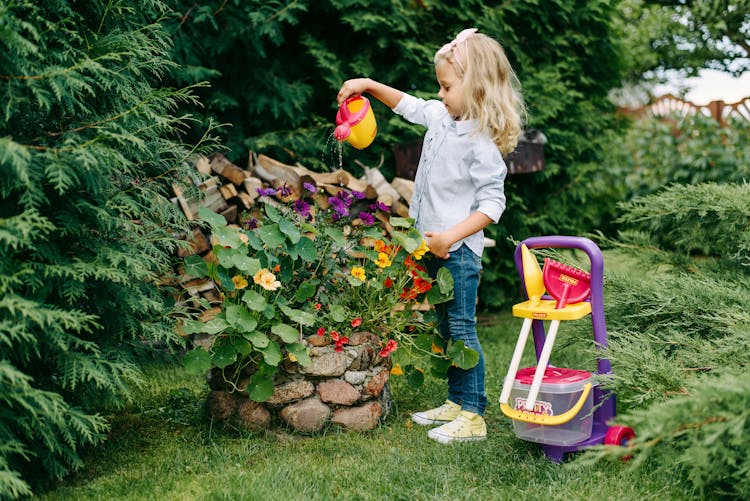 A Young Girl Watering A Plants