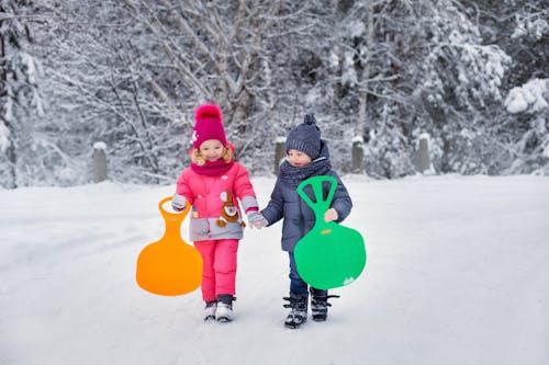 Child in Red and White Jacket and Pants Holding Red Heart Balloon on Snow Covered Ground