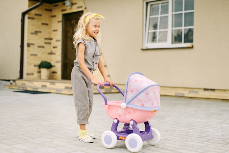 A Young Girl Pushing A Stroller Toy