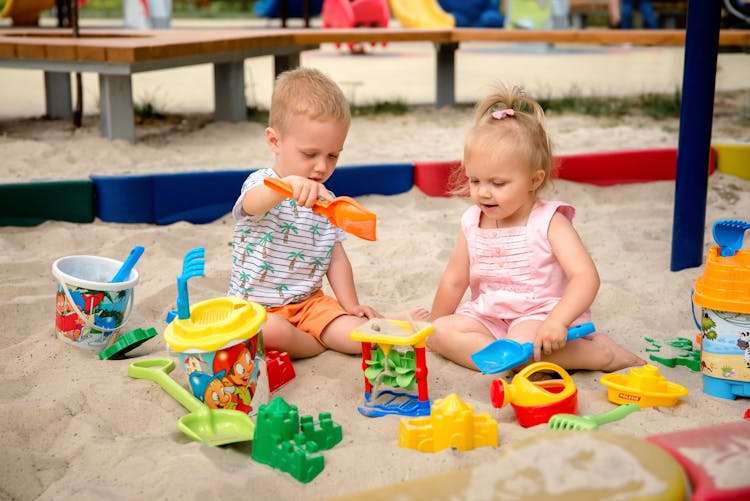 A Boy And Girl Playing Toys On A Sand 