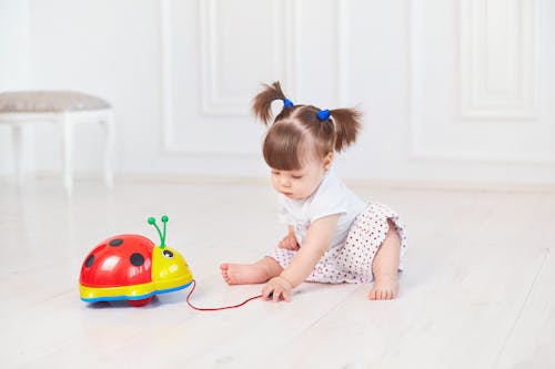 Toddler Sitting on the Floor While Playing with a Toy