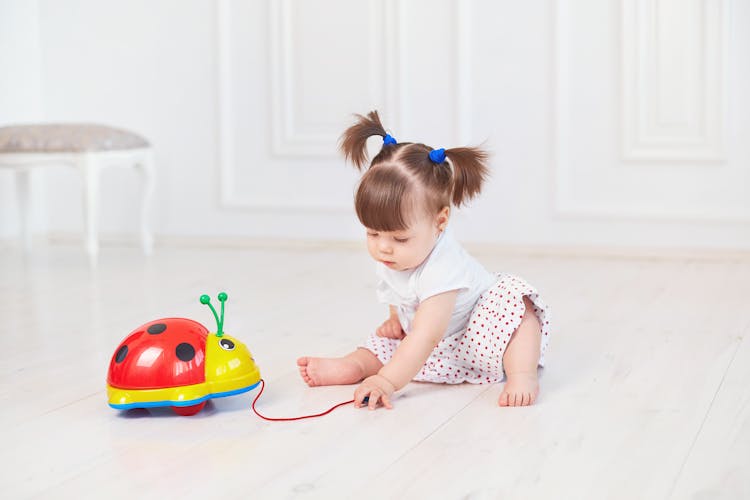 Toddler Sitting On The Floor While Playing With A Toy