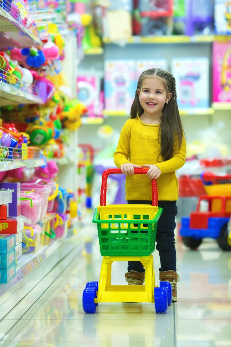 A Young Girl Pushing A Cart Toy