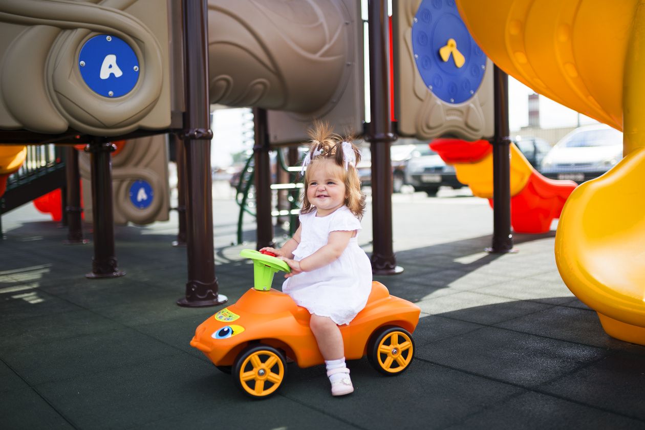 Best outdoor toys for 1 year old: toddler girl on a ride-on toy car