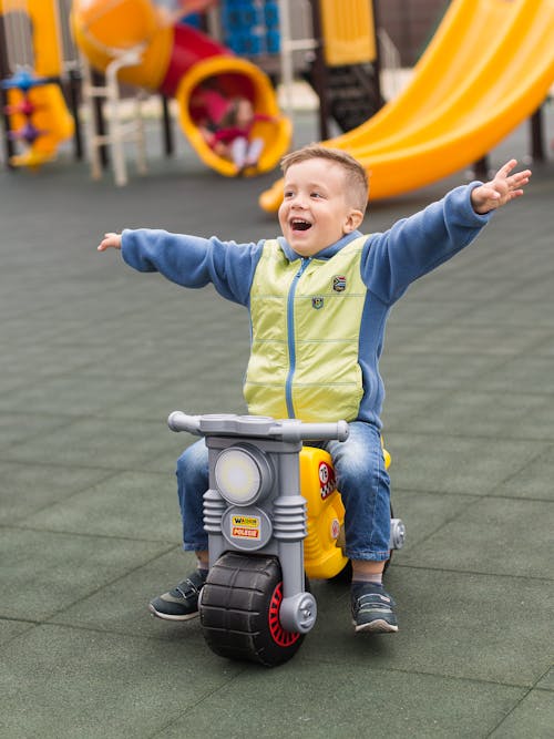 A Happy Boy Sitting on a Motorcycle Toy