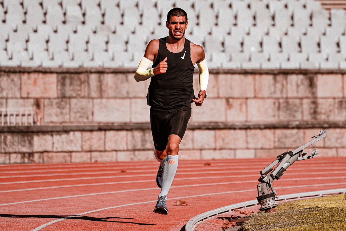 Male athlete running on a track wearing compression arm sleeves for joint support