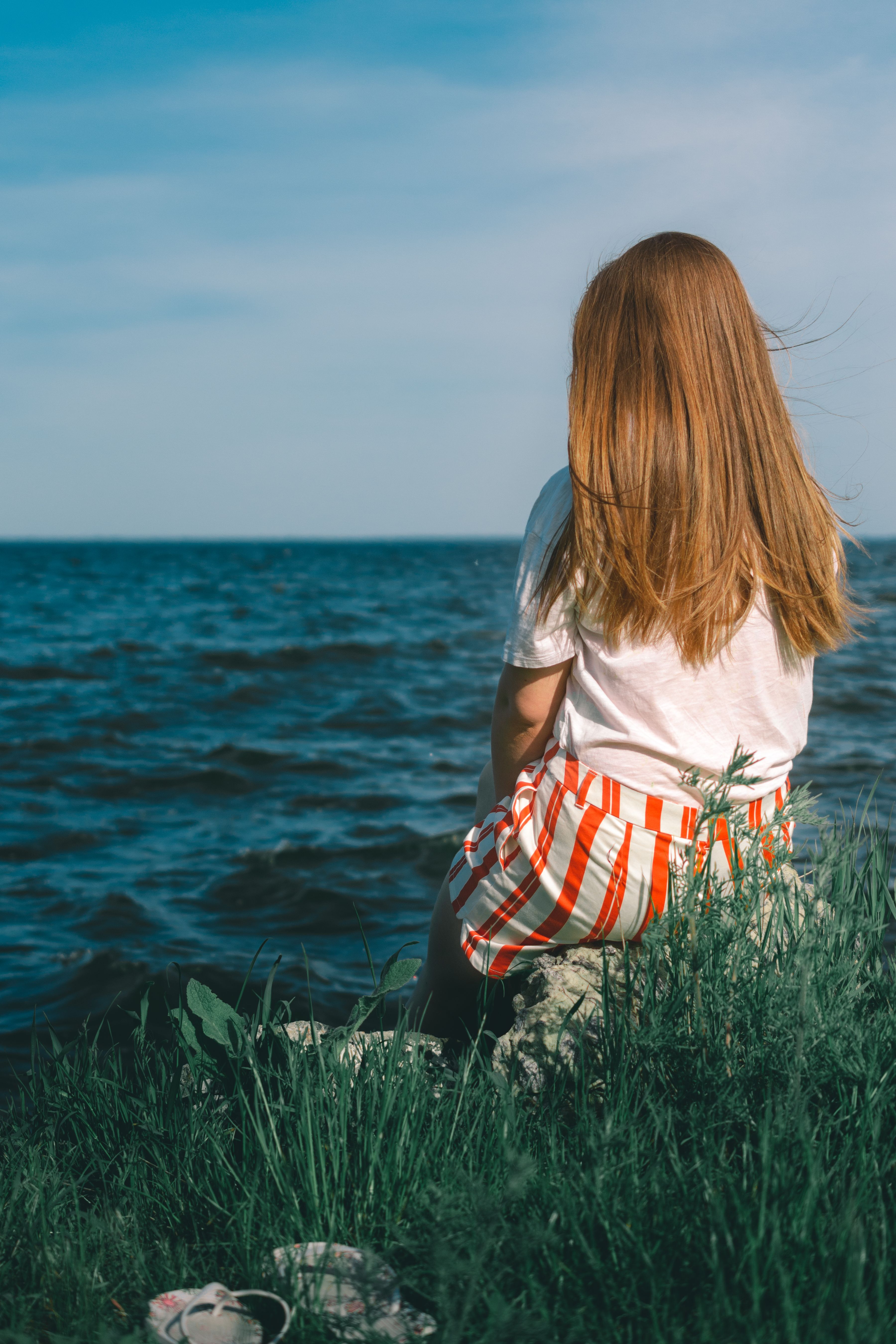 A Woman Sitting on a Seaside · Free Stock Photo